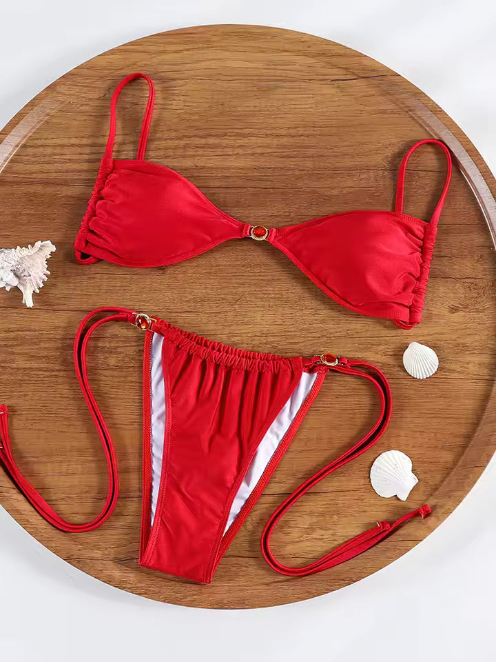 Red bikini set on a wooden tray with seashells.