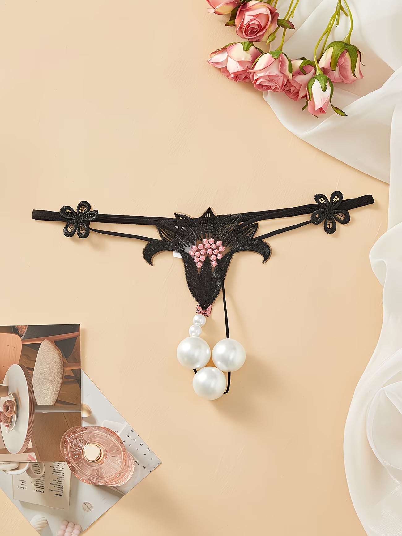 Close-up of Bikinisexzy black lace thong showing pink floral embroidery detail on sheer mesh fabric