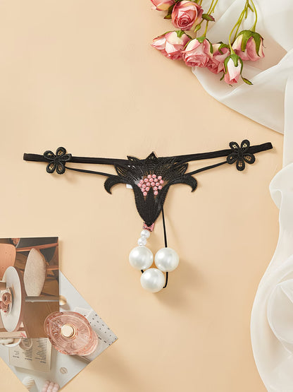 Close-up of Bikinisexzy black lace thong showing pink floral embroidery detail on sheer mesh fabric