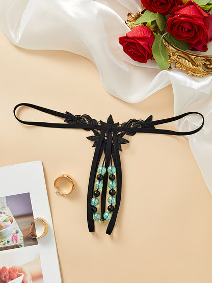 Black butterfly lace thong with glow-in-the-dark green beads flat lay styled with red roses – Bikinisexzy