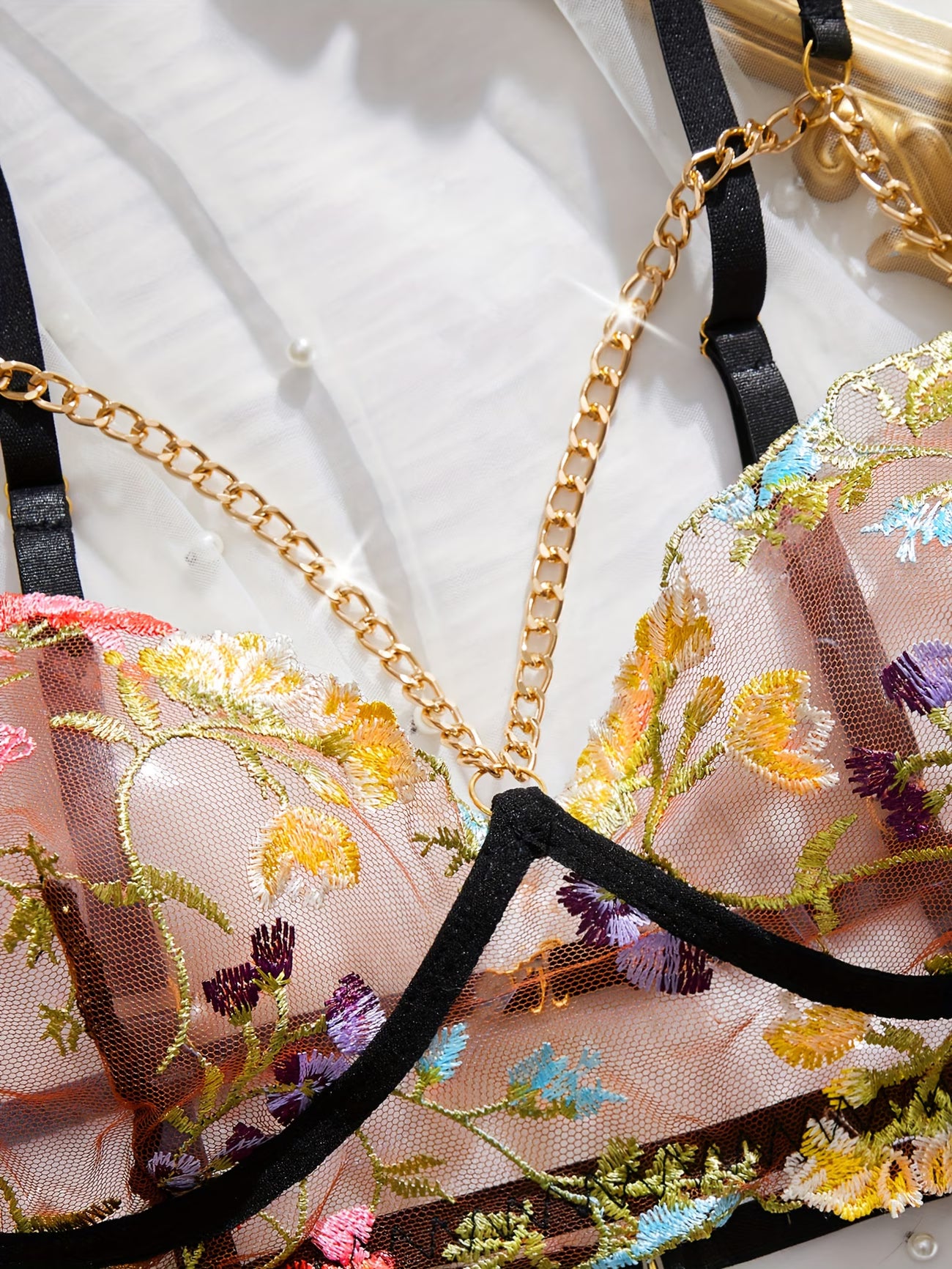 bikinisexzy Close-up of a floral embroidered lingerie set with gold chain details.