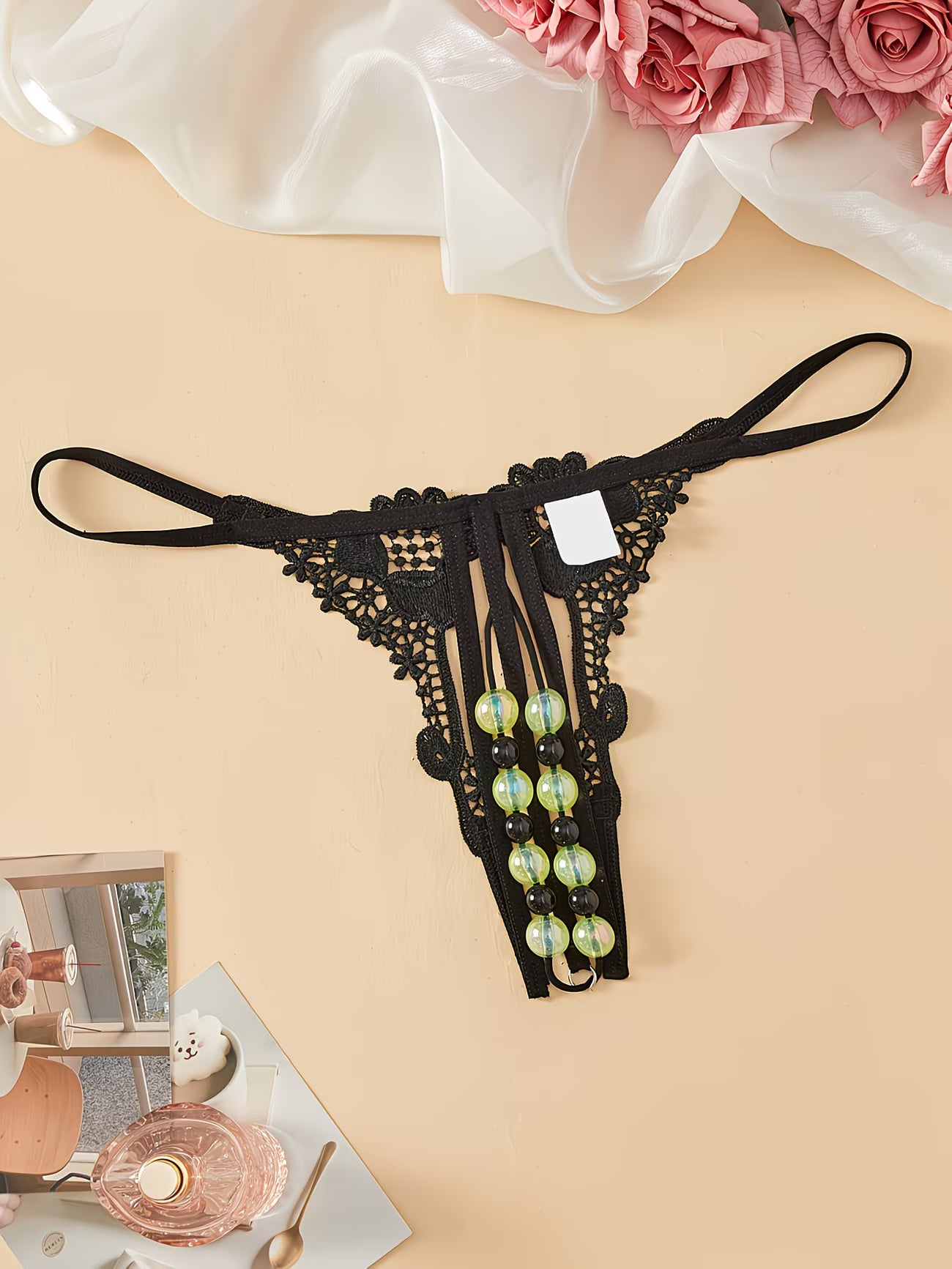 Bikinisexzy open-crotch lace thong with double row glow pearls – product tag visible, flat lay styling

