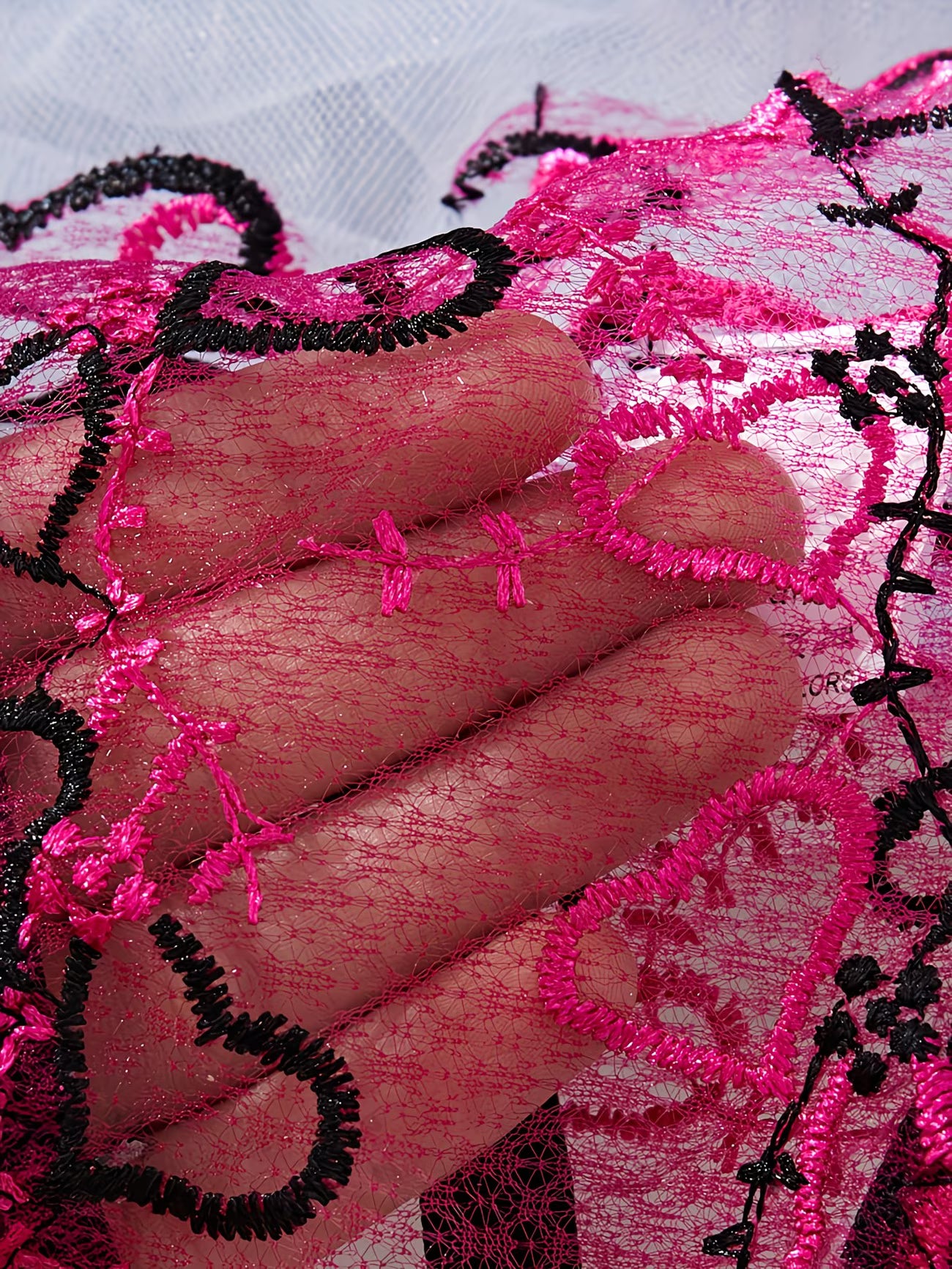 Close-up of sheer pink and black embroidered heart lace fabric - Bikinisexzy