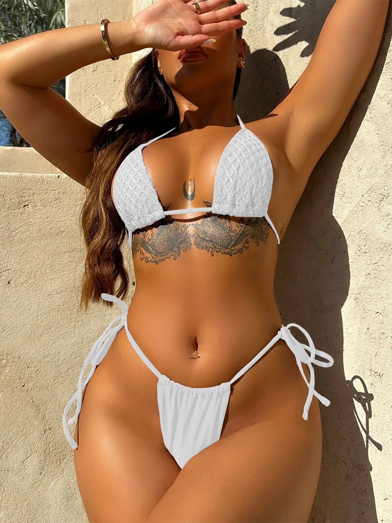 Person wearing a white bikini against a beige wall. Sexy beachwear collection BIKINISEXZY summer style